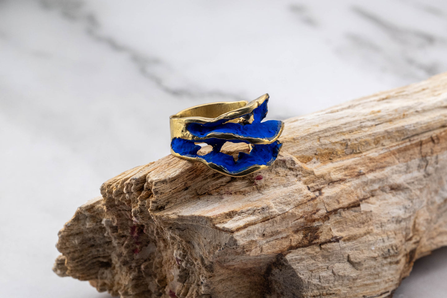 Gold-tone ring top with bright blue resin flower detail on band