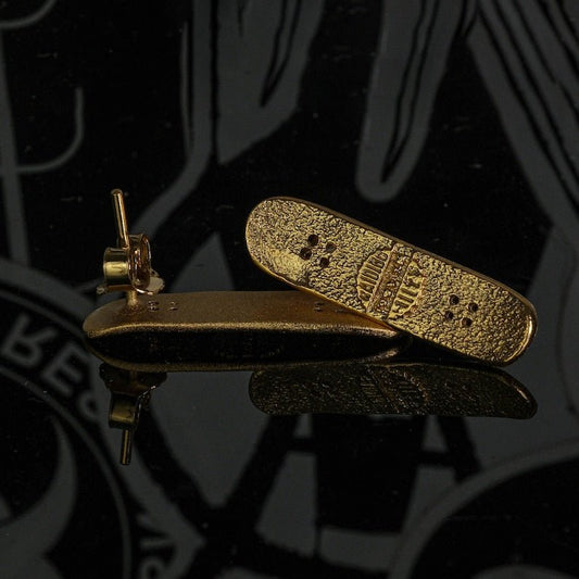 Skateboard stud earrings in gold tone, skateboard-shaped studs with perforation details.