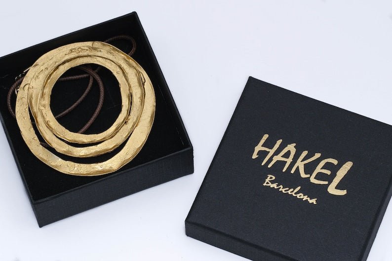 Gold spiral pendant necklace with braided cord, flat round double-ring design
