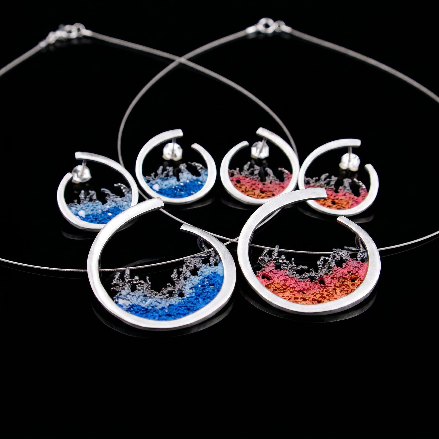 Set of silver hoop earrings with blue and red resin splash designs