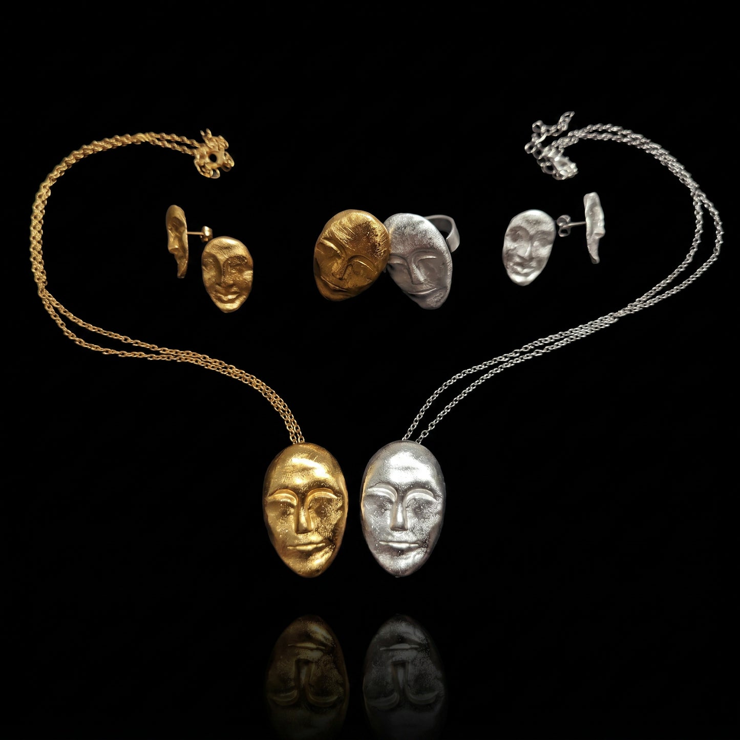 Gold and silver oval face rings with sculpted facial designs and wide bands