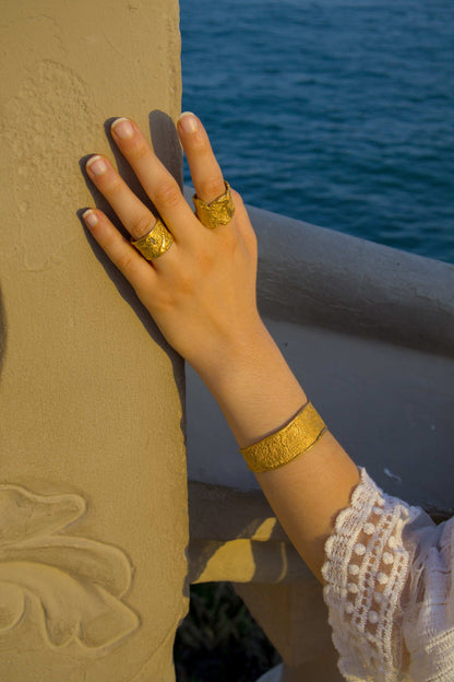 Gold cuff bracelet on hand with textured face and curved opening
