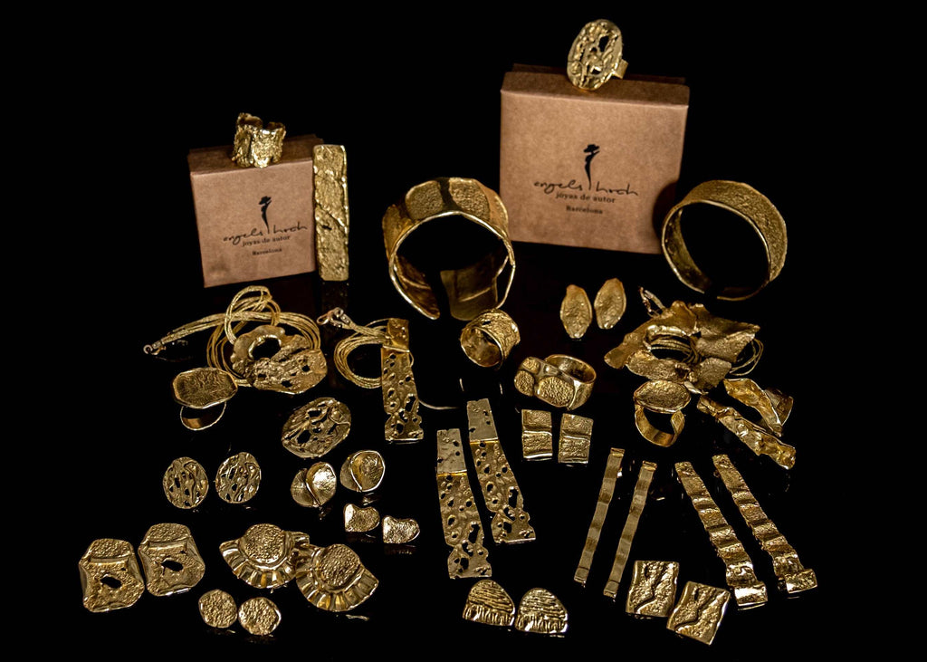 Anell d'or martellejat entre diversos accessoris d'or, petits anells i arracades a prop
