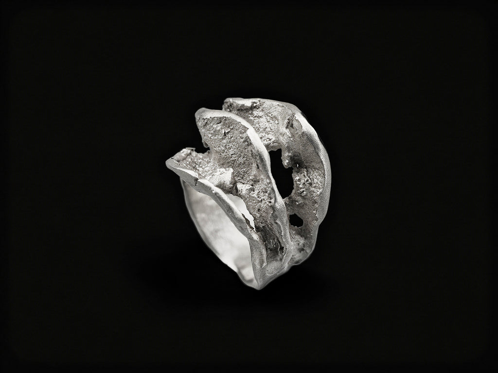 Silver sculpted ring with rough, wave-like textured band and raised top form
