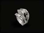 Silver sculpted ring with rough, wave-like textured band and raised top form