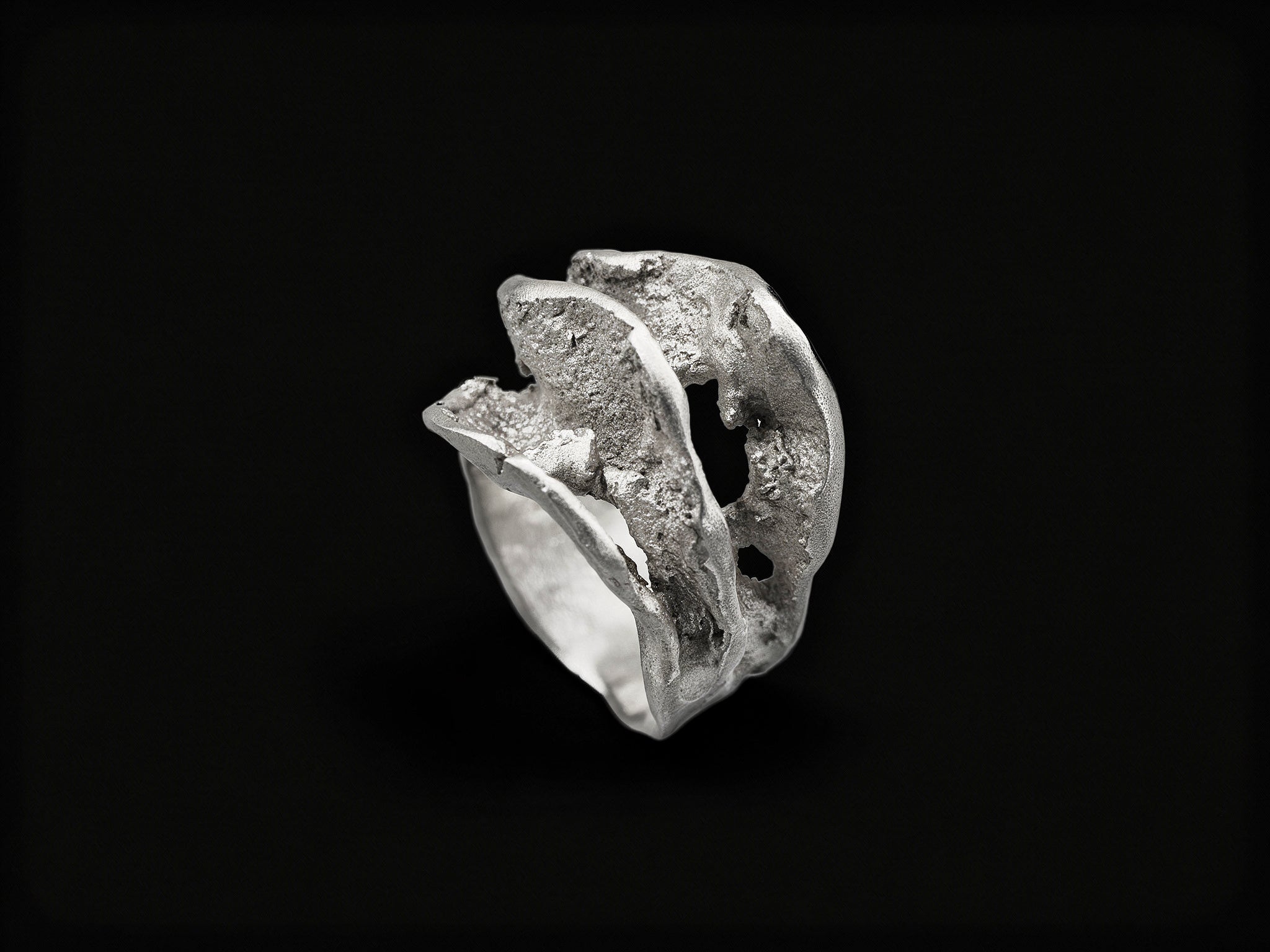 Silver sculpted ring with rough, wave-like textured band and raised top form