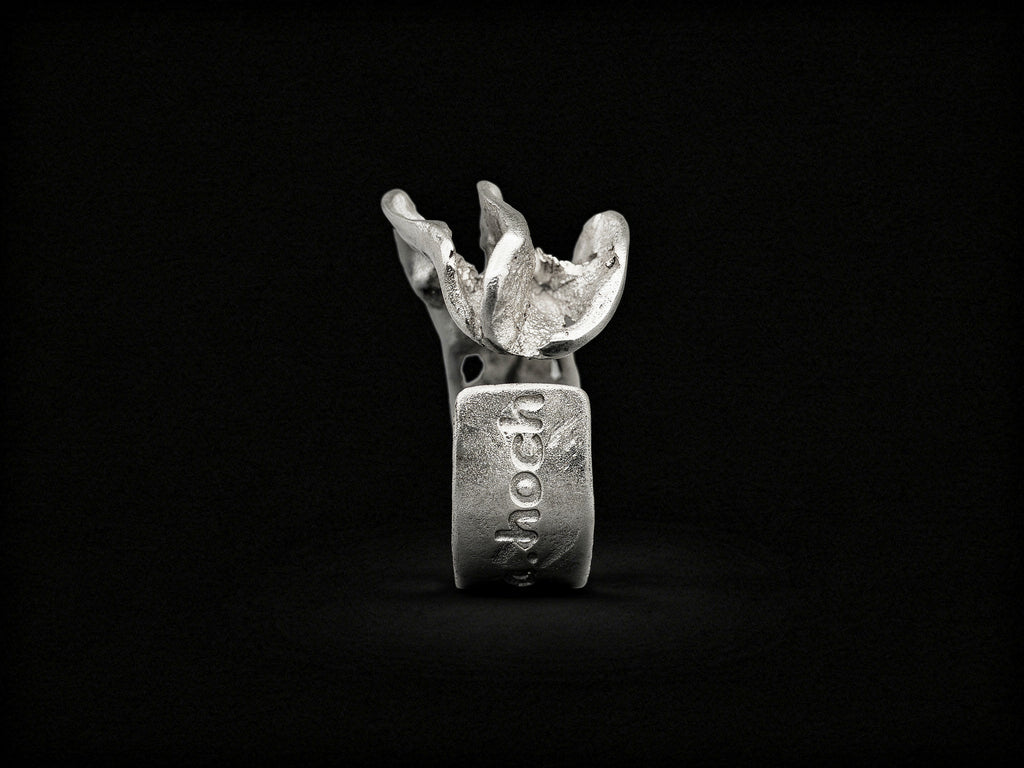 Silver sculpted ring, front view with raised jagged crest and stamp on band