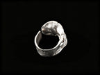 Silver sculpted ring side view with open, wave-like metalwork and raised top