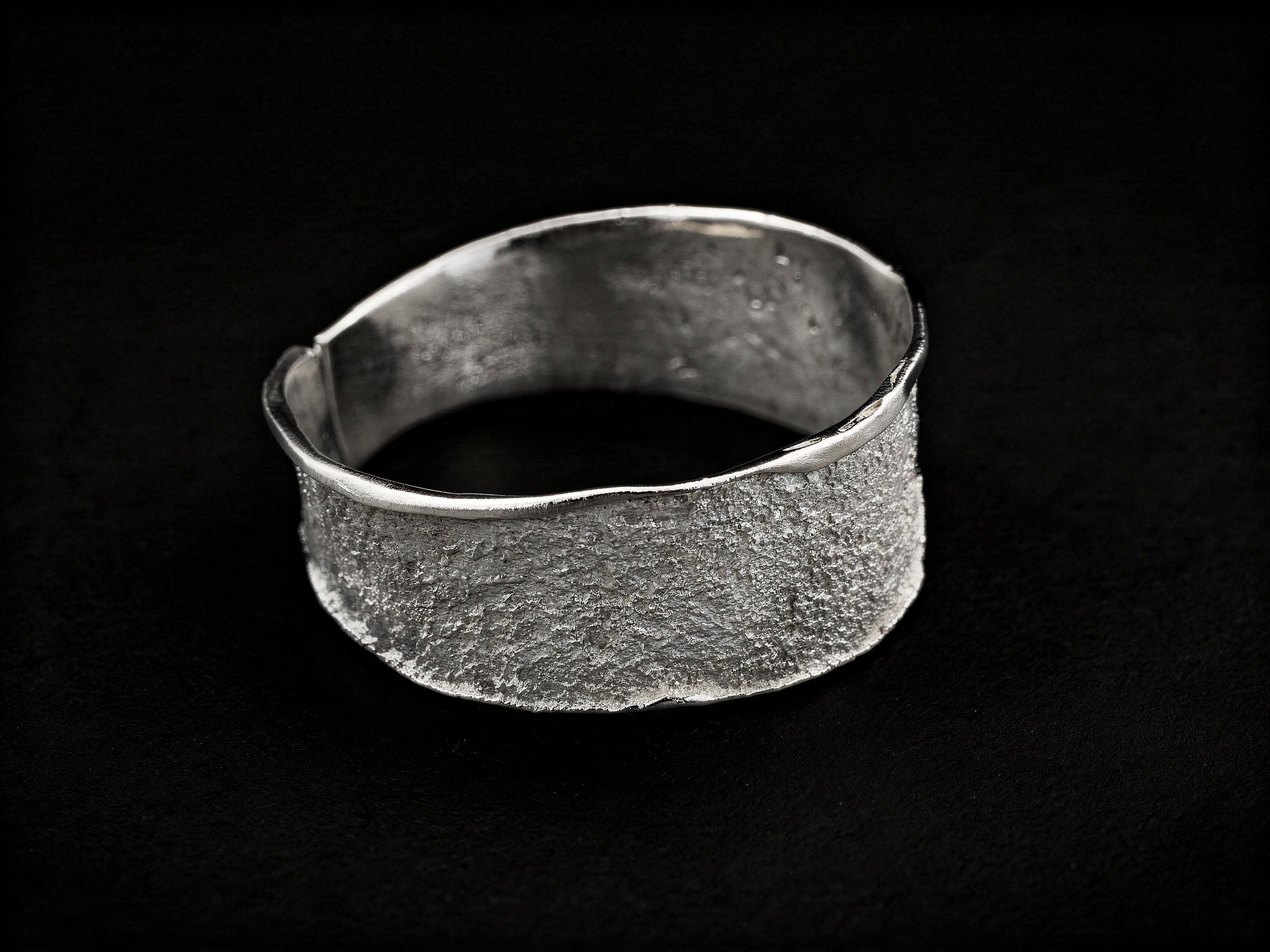 Silver textured cuff bracelet with wide band and smooth open-ended interior