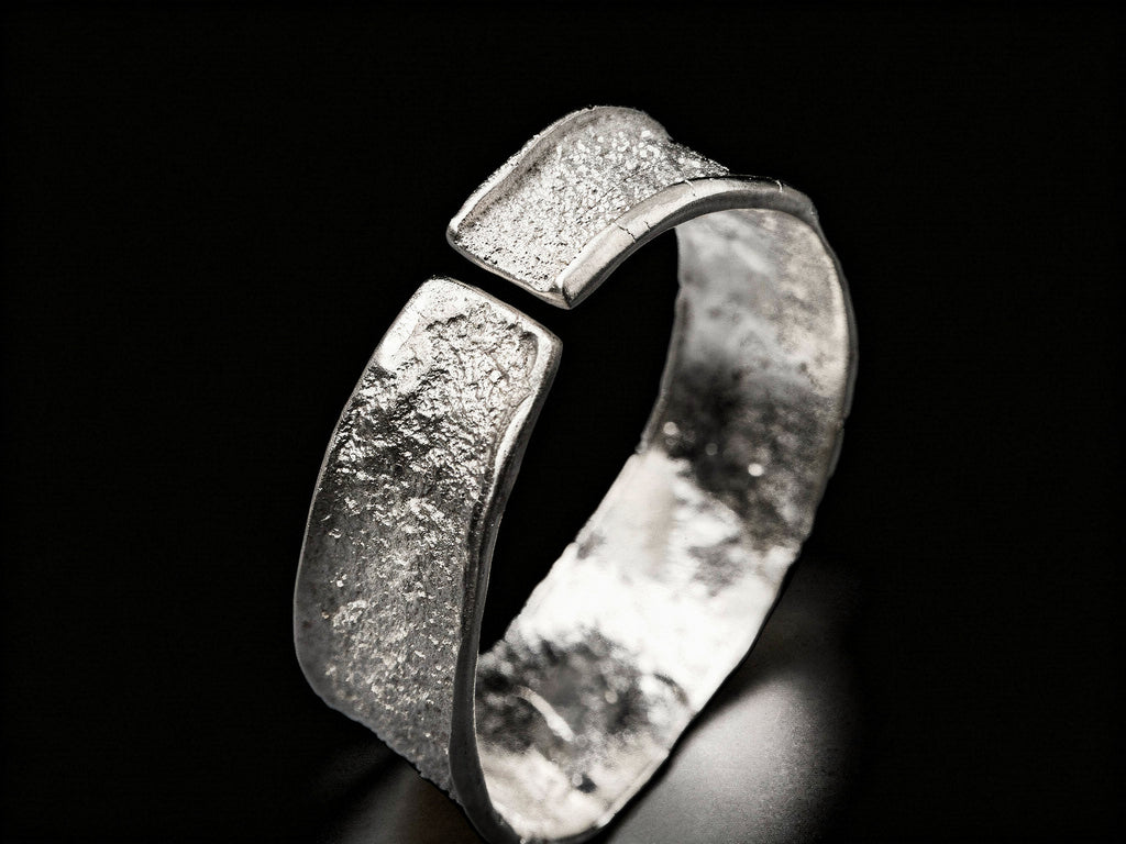 Silver hammered cuff bracelet, angled view with wide top and visible inner band
