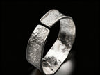 Silver hammered cuff bracelet, angled view with wide top and visible inner band