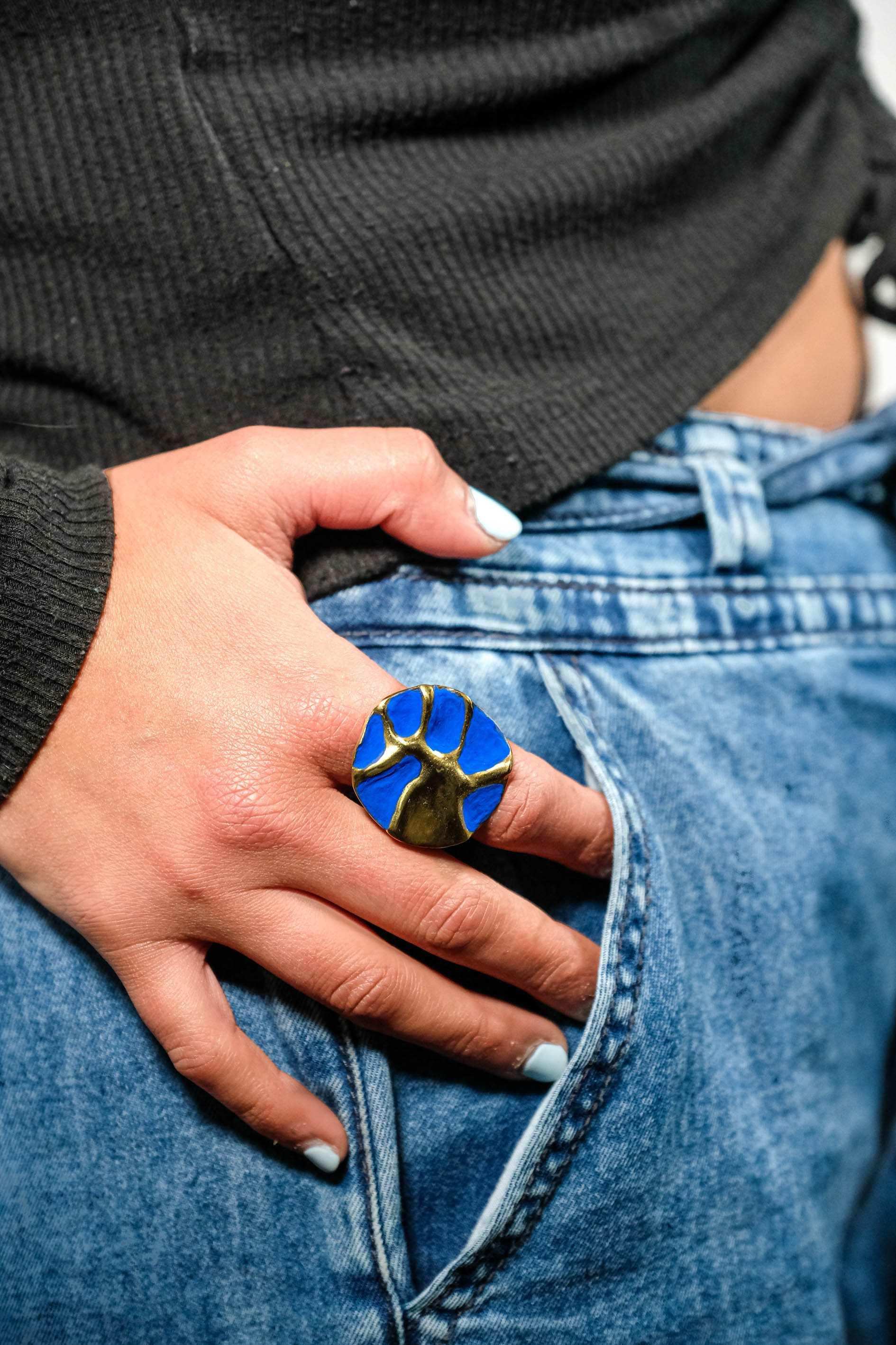 Blue enamel concept ring on hand, gold-tone sculpted design