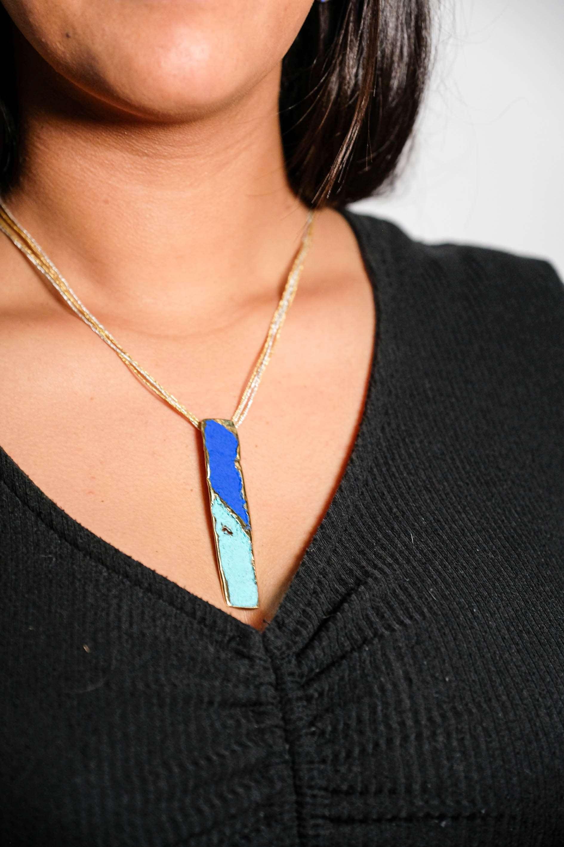 Gold-tone pendant necklace with blue and turquoise enamel teardrop pendant at neckline