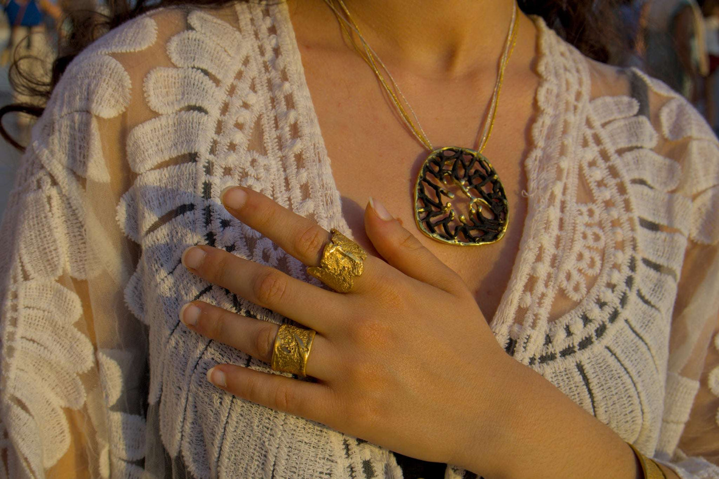 Orbis pendant on thin gold chain with dark round filigree medallion and gold rim