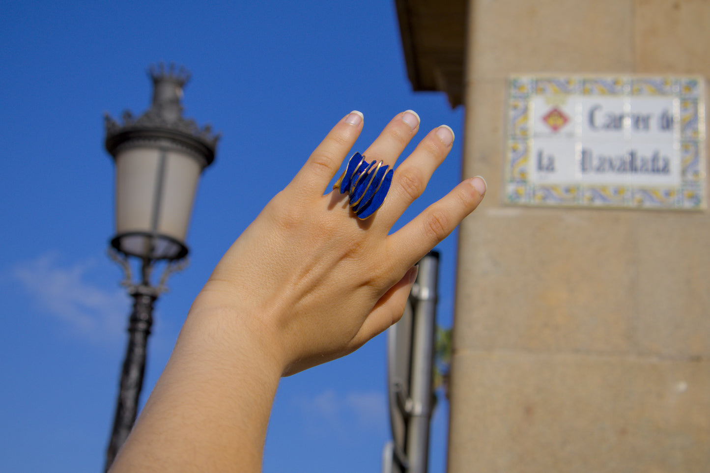 Gold-tone ring with blue spiral inlay on finger