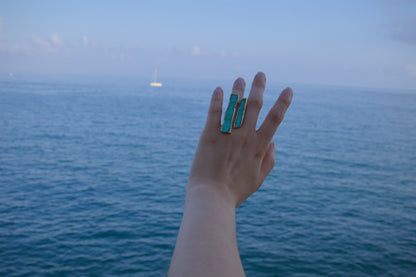 Turquoise enamel rings on raised hand with gold-tone bands