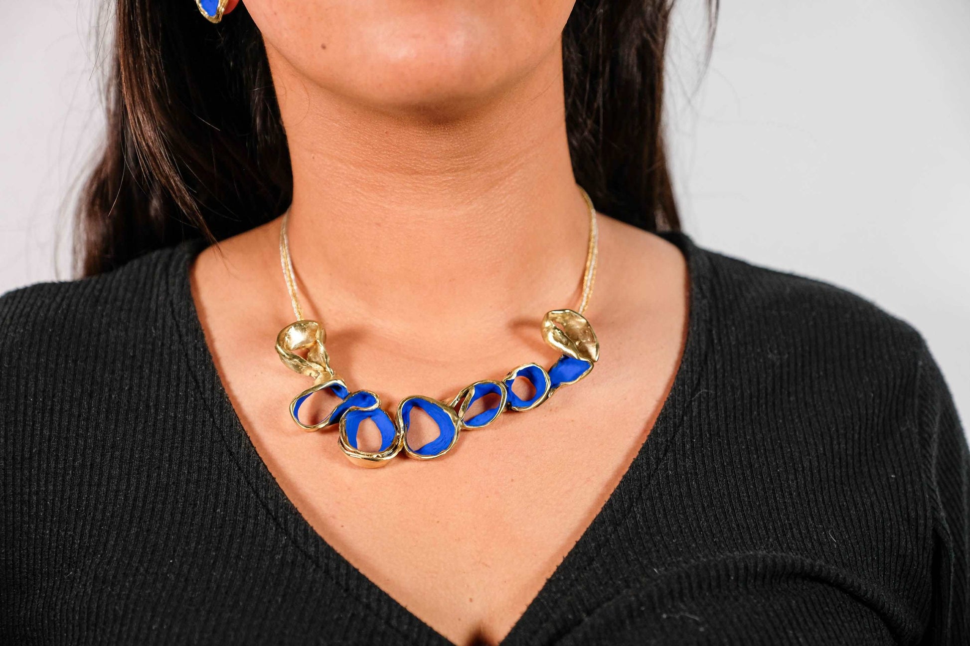 Gold-tone necklace with blue oval link beads, centered at the neckline