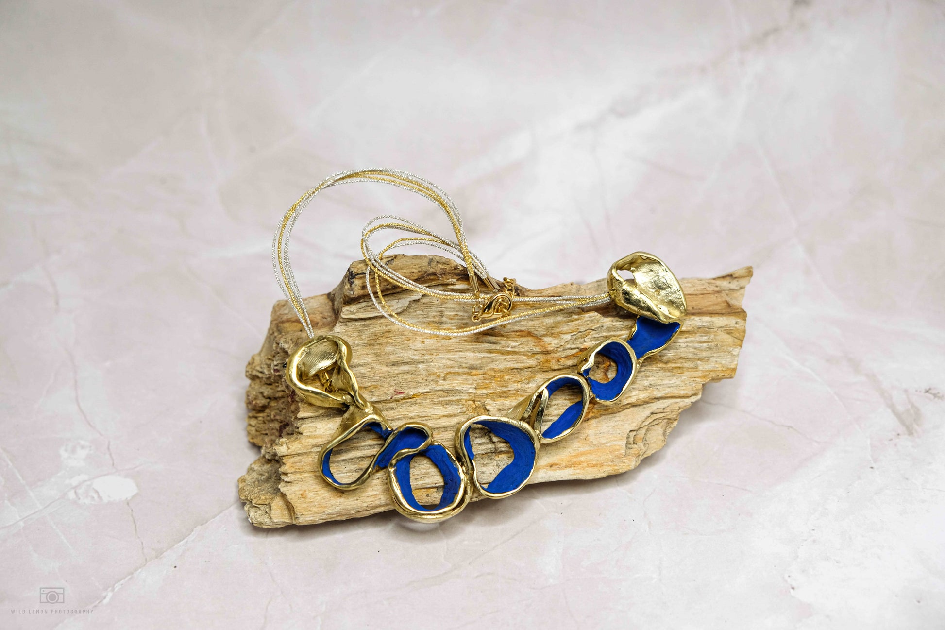 Gold-tone Ocean Harmony necklace with blue oval link beads on driftwood