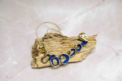 Gold-tone Ocean Harmony necklace with blue oval link beads on driftwood