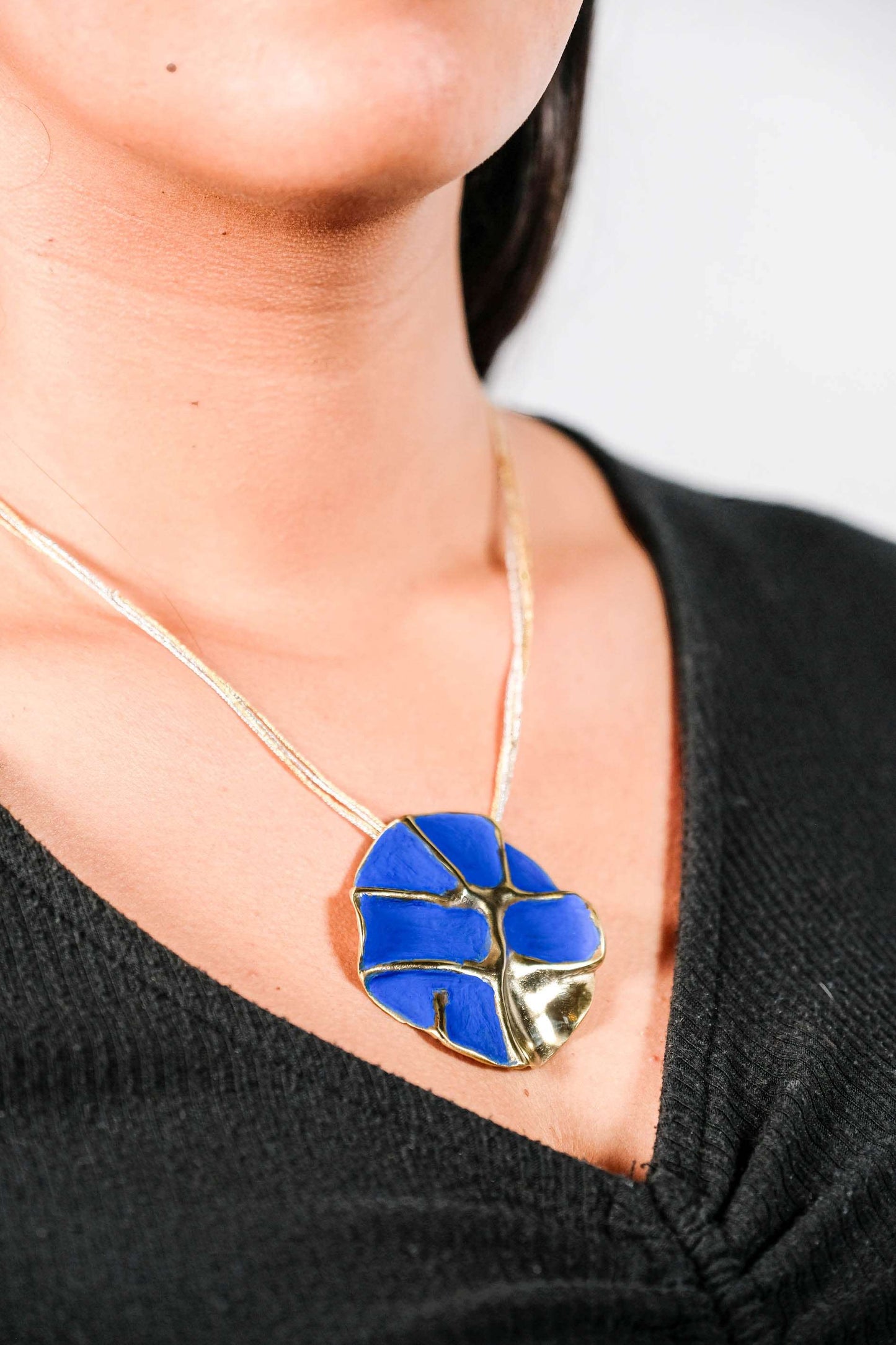 Gold-tone concept necklace with blue enamel flower pendant on thin chain