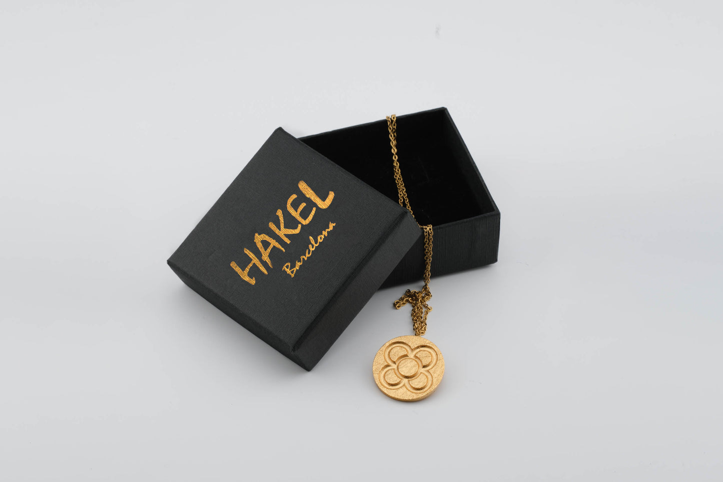 Gold round flower pendant on chain, shown with black gift box