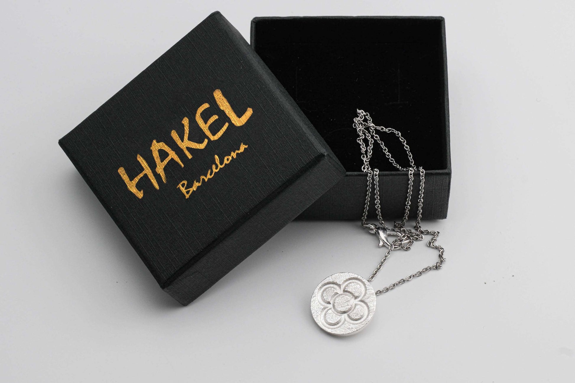 Gold and silver round flower pendant necklaces on chains, with black gift boxes