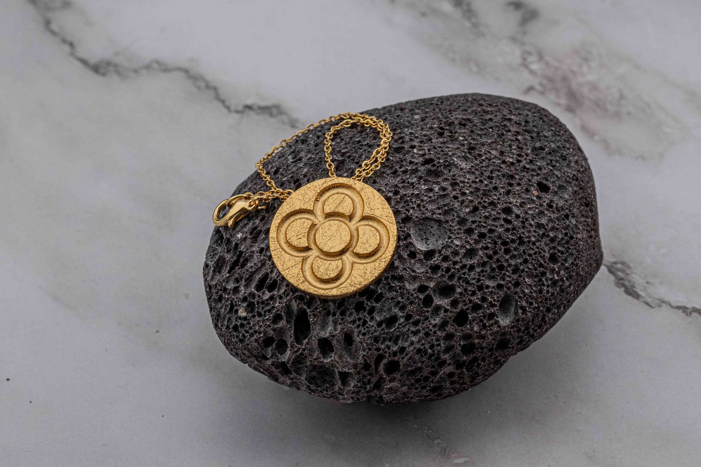 Gold round flower pendant on chain, textured circular embossed flower motif