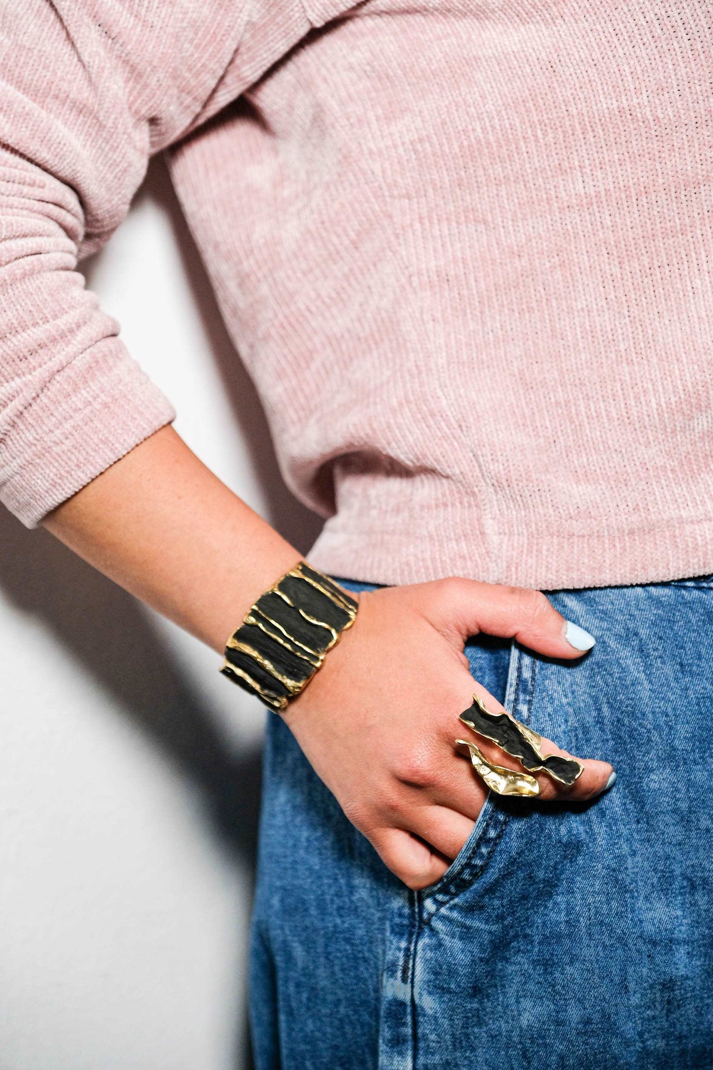Black sculpted cuff bracelet with gold ridges worn on wrist