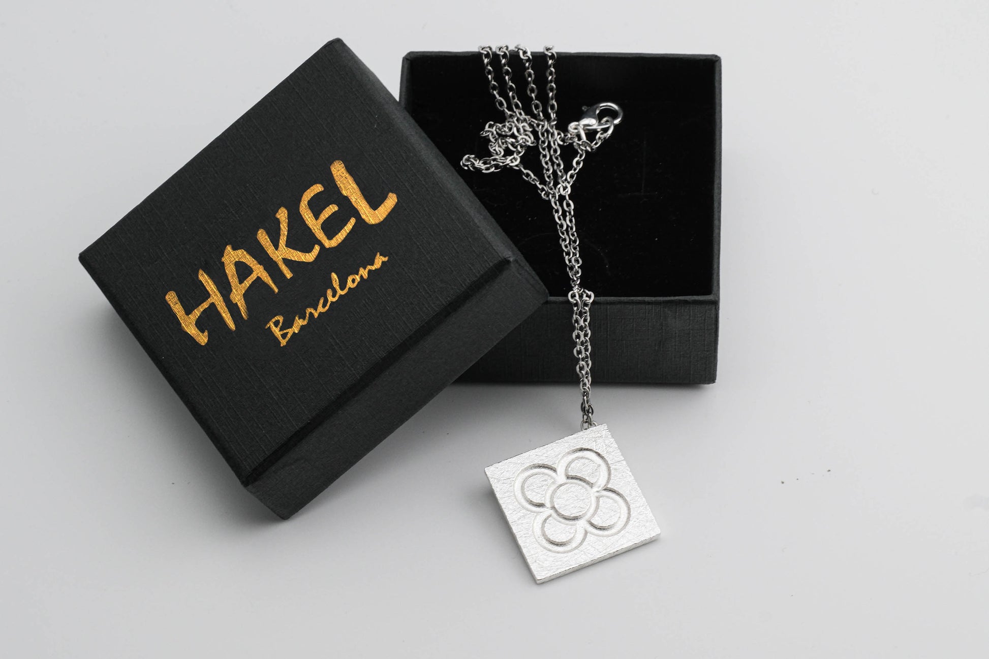 Silver square flower pendant on chain, shown with jewelry box
