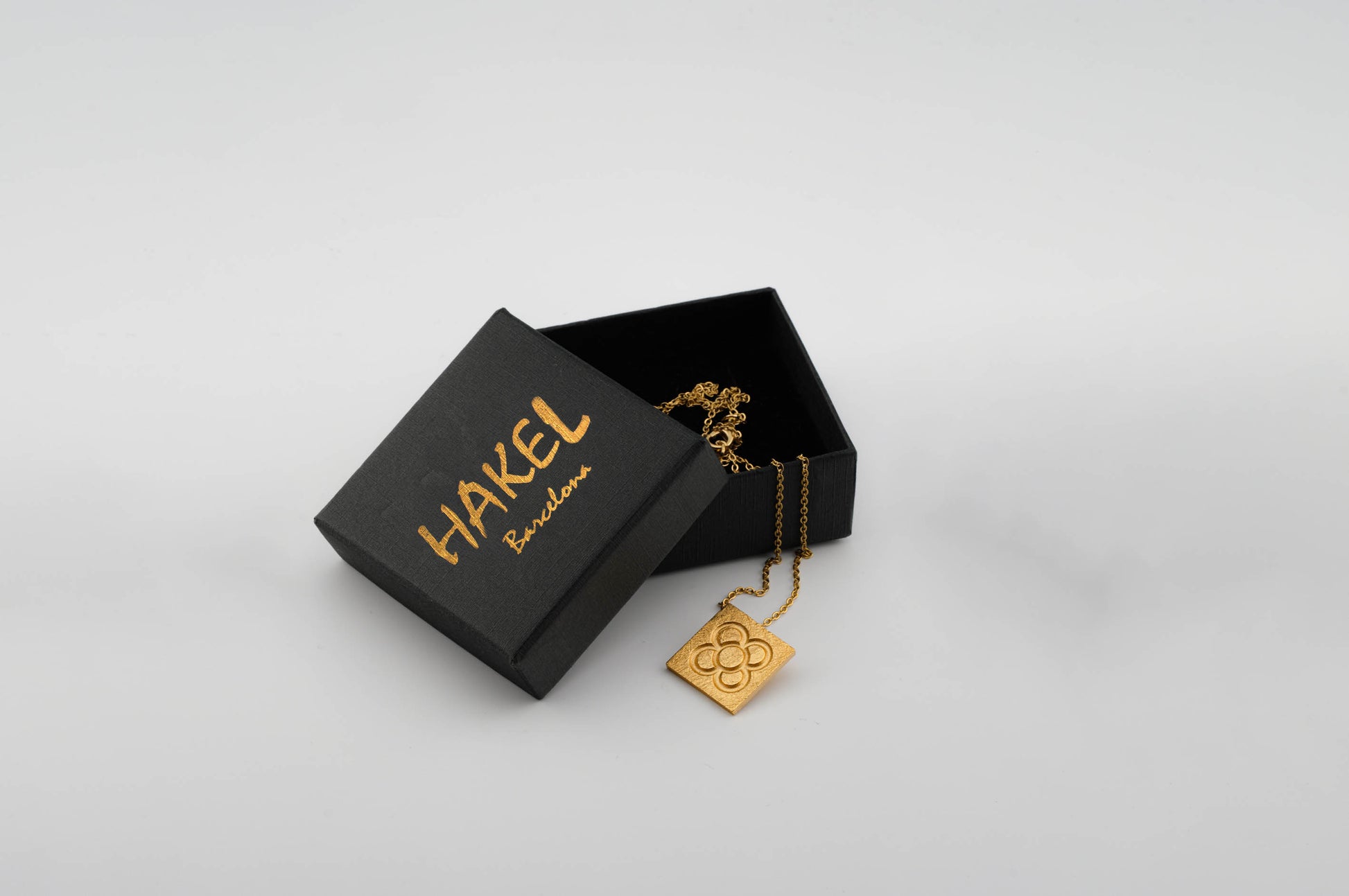 Gold square flower pendant on chain, shown with jewelry box