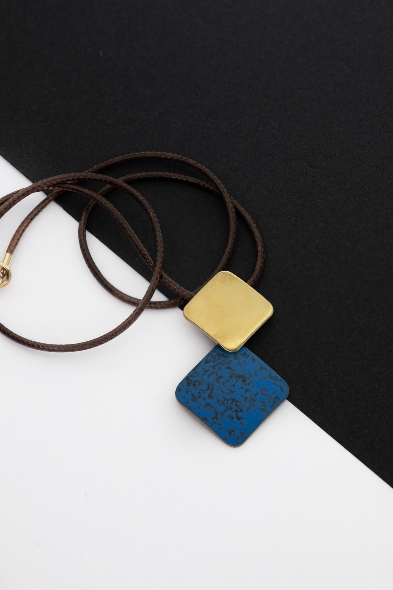 Pendant necklace with brown cord, gold-tone square charm, blue speckled charm