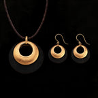 Gold-tone pendant and hoop earrings set with smooth black-backed discs and open centers