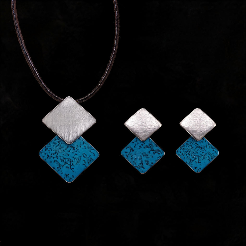 Silver-tone necklace with three stacked diamond charms: brushed silver and turquoise enamel