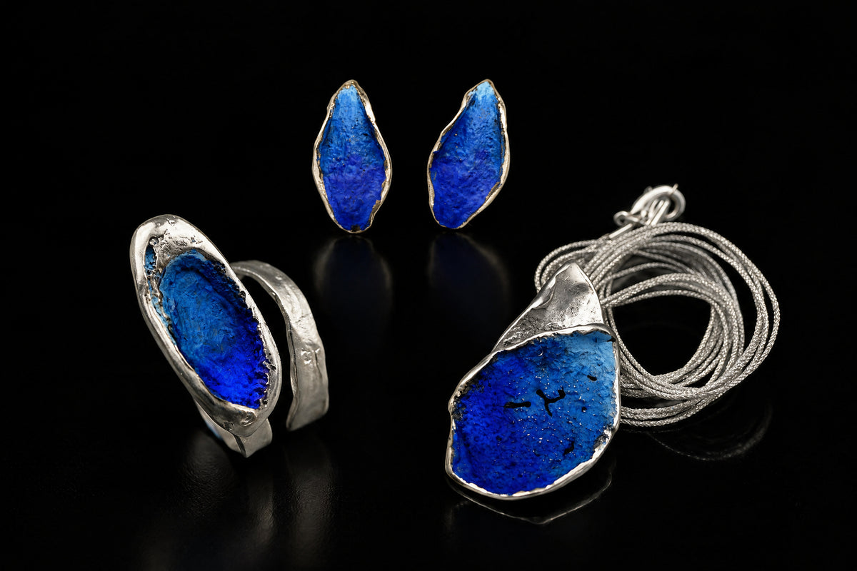 Silver Echo Ring with a cobalt blue inset, shown beside matching blue earrings and pendant.