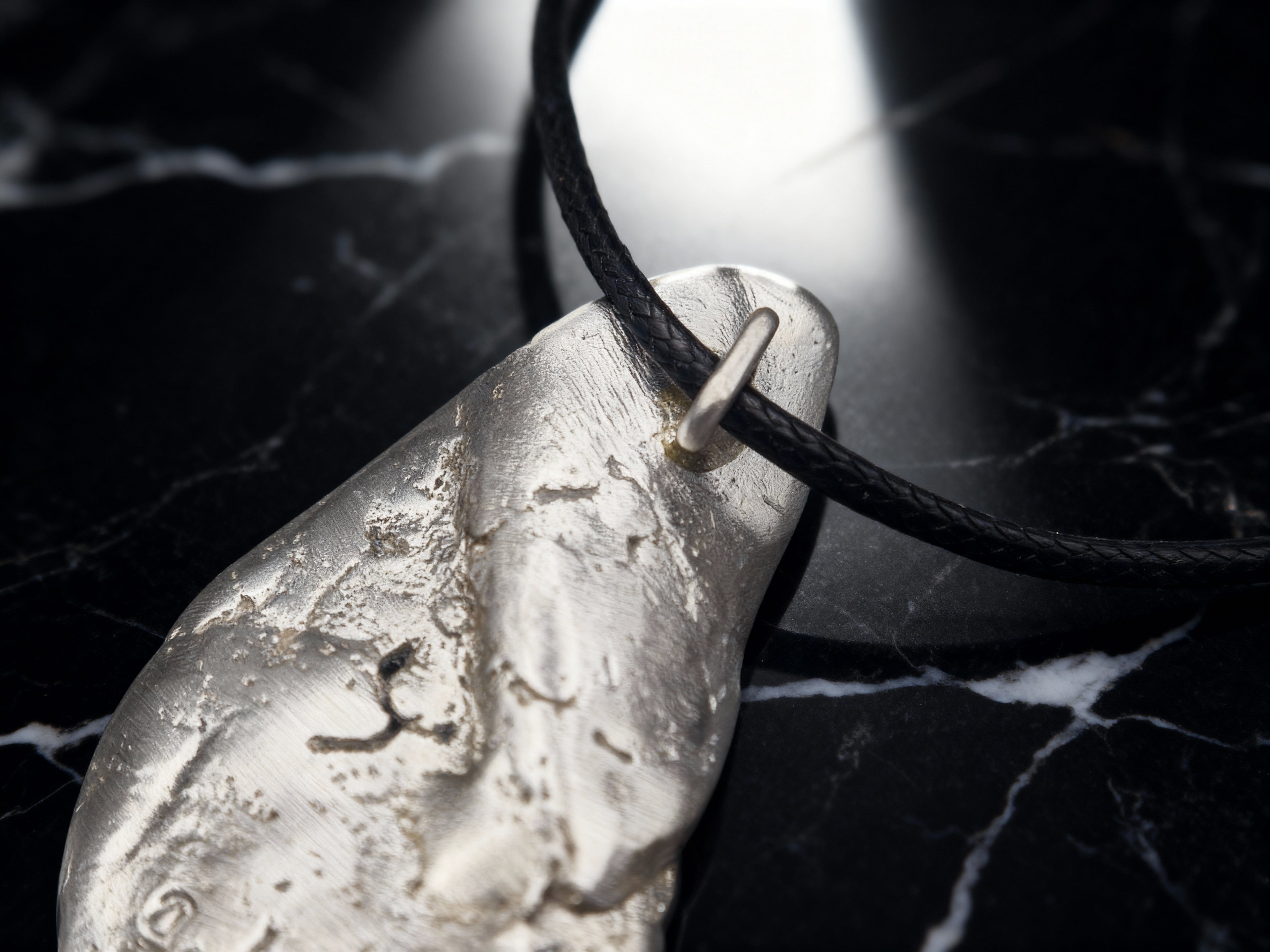 Silver-tone teardrop pendant close-up on black cord