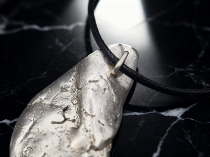 Silver-tone teardrop pendant close-up on black cord