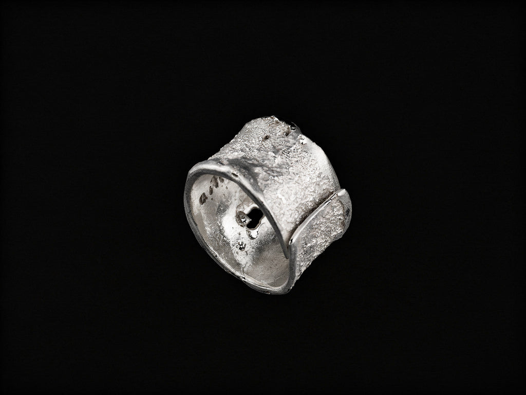 Anell de plata amb textura amb part superior corbada i detall d'incrustacions fosques