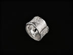 Anell de plata amb textura amb part superior corbada i detall d'incrustacions fosques