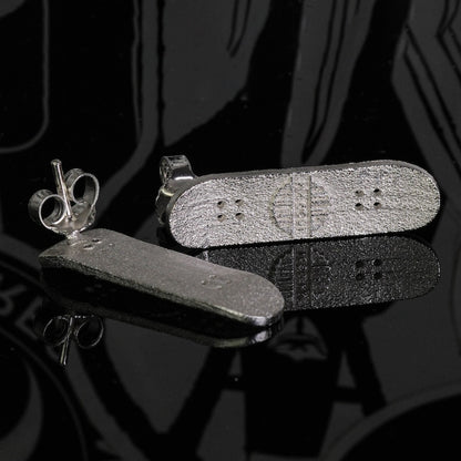 Skateboard stud earrings in silver tone, skateboard-shaped studs with small holes.