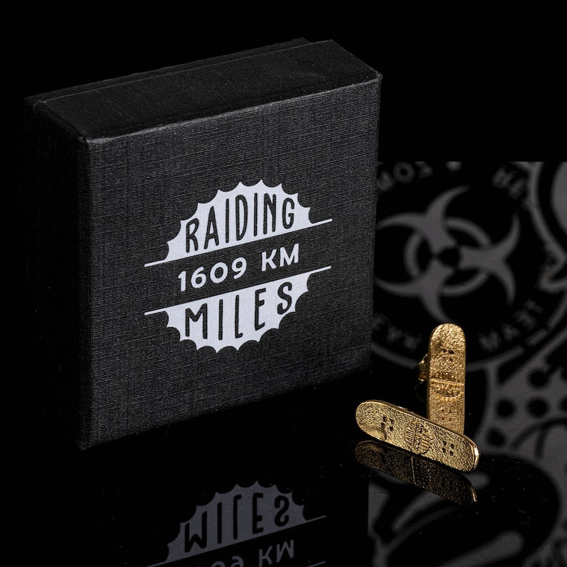 Gold skateboard stud earrings, shown with a dark gift box.