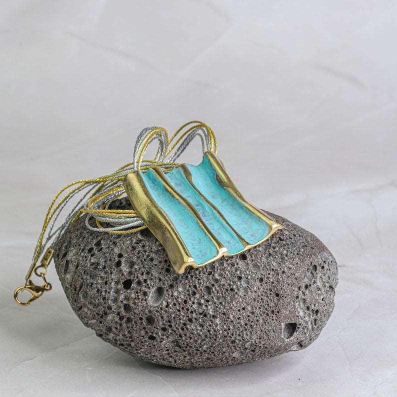 Turquoise and gold striped pendant necklace with braided cord hanging