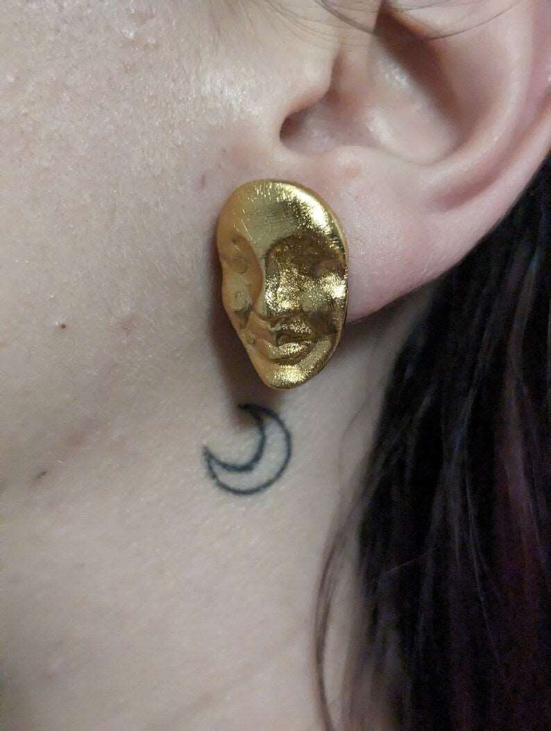 Gold oval face stud earrings on ear, textured metallic finish