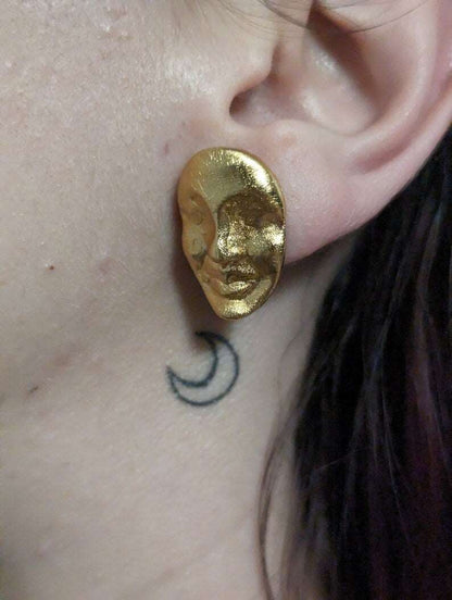 Gold oval face stud earrings on ear, textured metallic finish