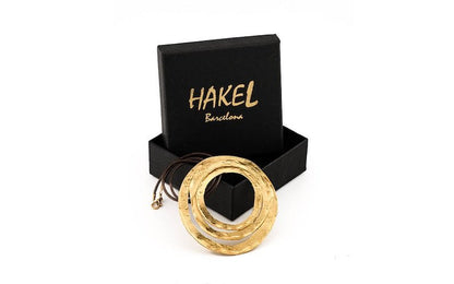 Gold circular pendant necklace with braided cord, shown in gift box