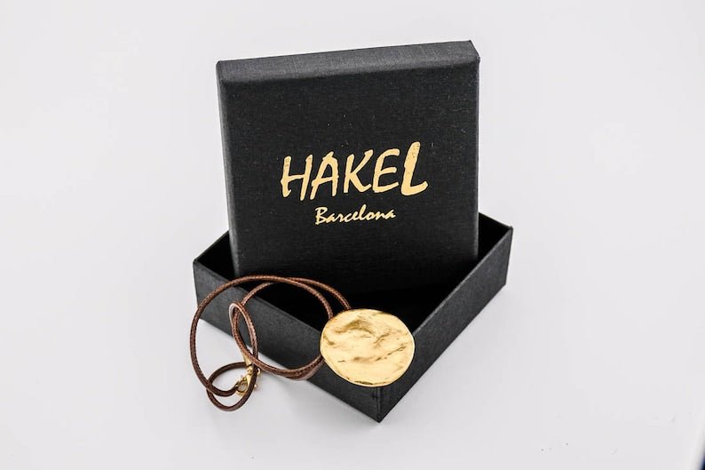 Gold disc pendant necklace with brown cord in black gift box