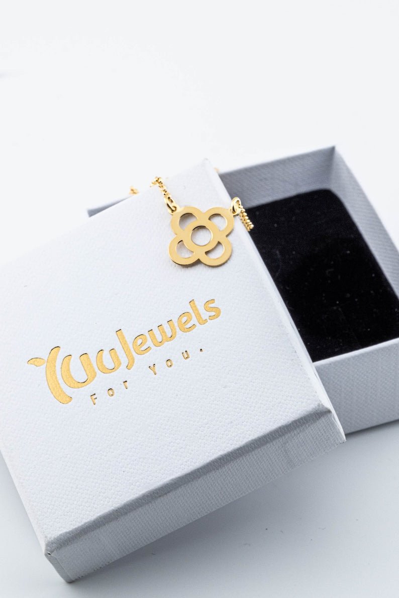 Gold flower pendant necklace resting in a white jewelry box with link chain.