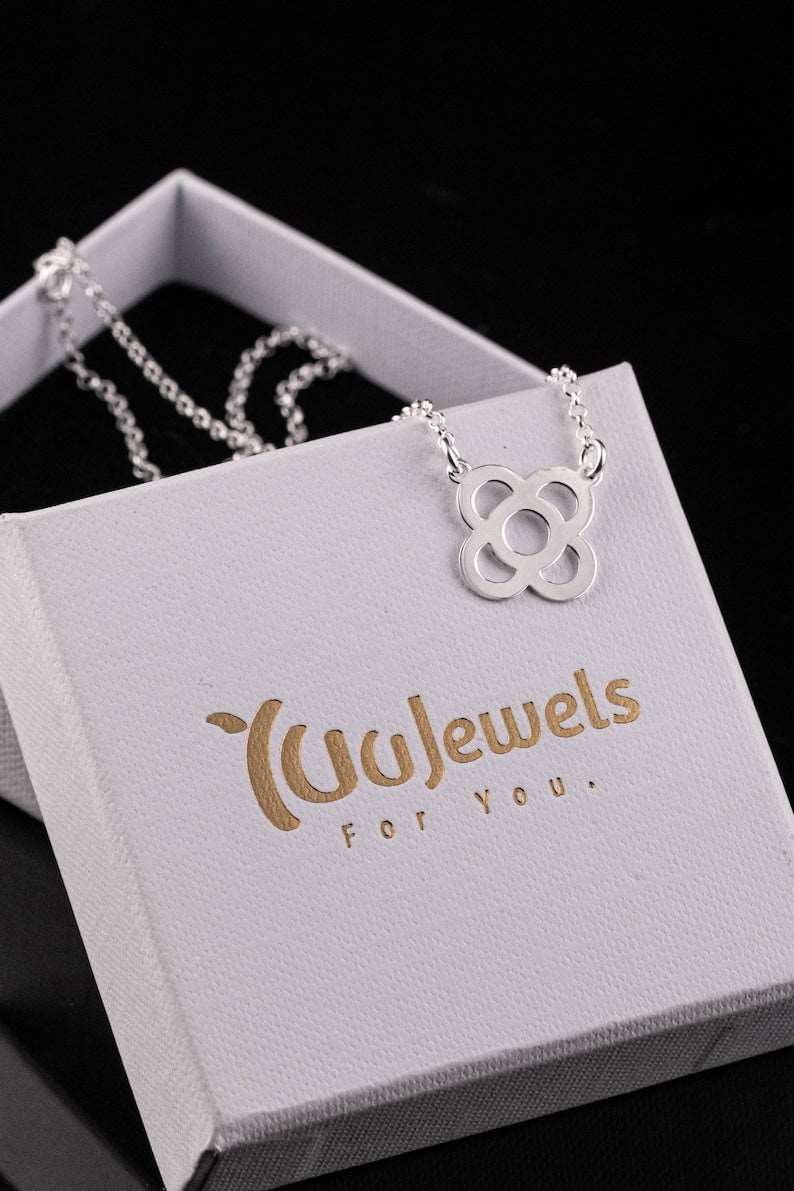 Silver flower pendant necklace on a white jewelry box with petal-shaped charm.