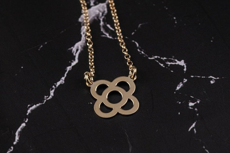 Gold flower pendant necklace with link chain and petal-shaped circular charm.