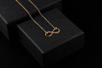Gold infinity pendant necklace with fine chain on black display box