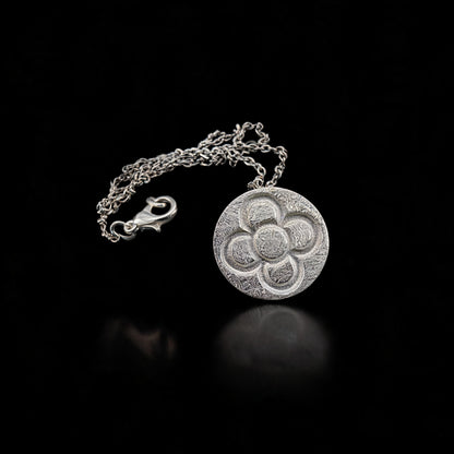 Round silver flower pendant with chain and clasp, circular textured design